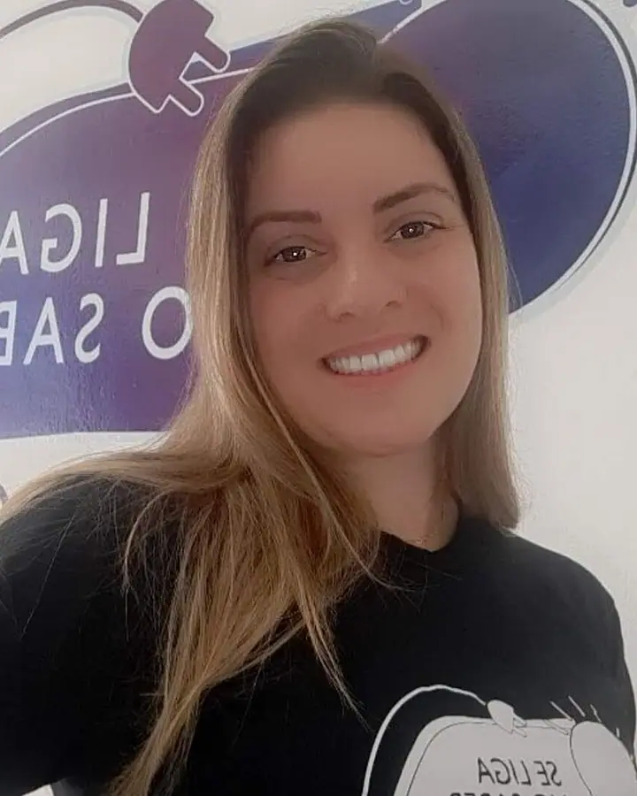 Fernanda Bueno, coordenadora do Se Liga no Saber, sorrindo, de camiseta preta com o logo da escola