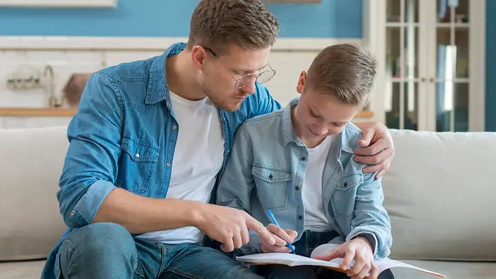 Pai e filho estudando juntos no sofá