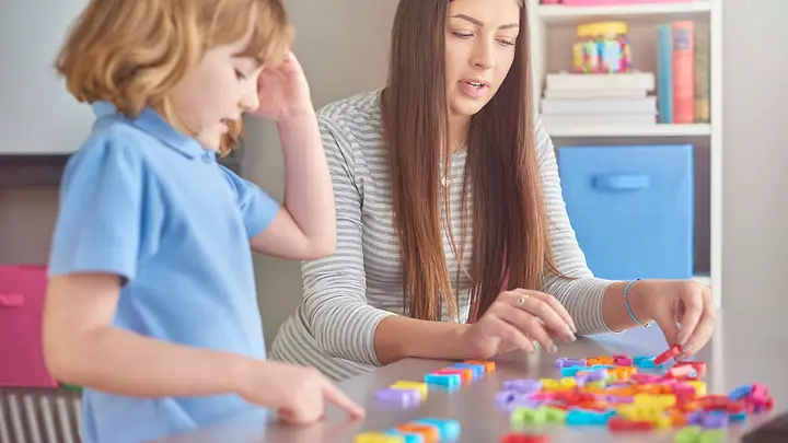 Professora e criança brincando com letras de encaixe