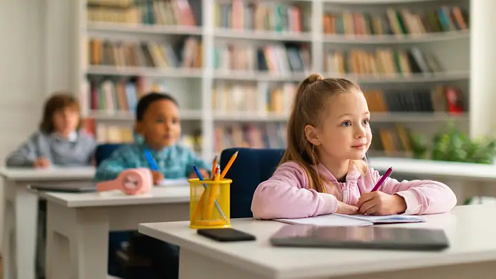 Alunos em sala de aula com estantes de livros ao fundo